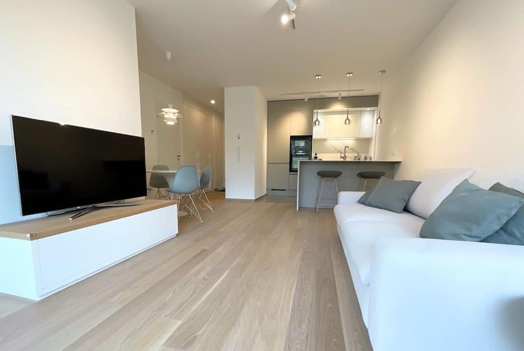 uma sala de estar com um sofá branco e uma televisão de ecrã plano em Kirchberg Apartment - High End 1 bedroom Apartment with terrace & parking em Luxemburgo