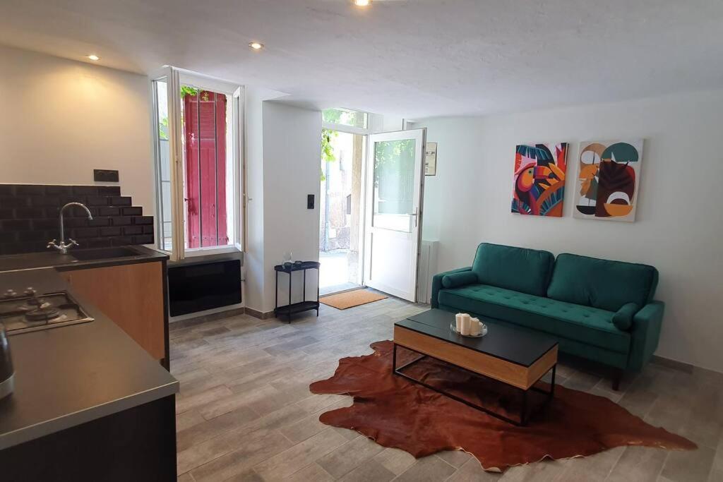 ein Wohnzimmer mit einem grünen Sofa und einem Tisch in der Unterkunft Studio en plein cœur de la ville in Mazan