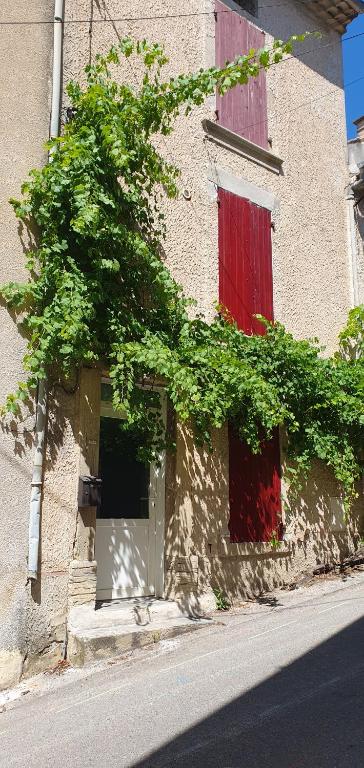 a building with two red doors and a window at Studio en plein cœur de la ville in Mazan
