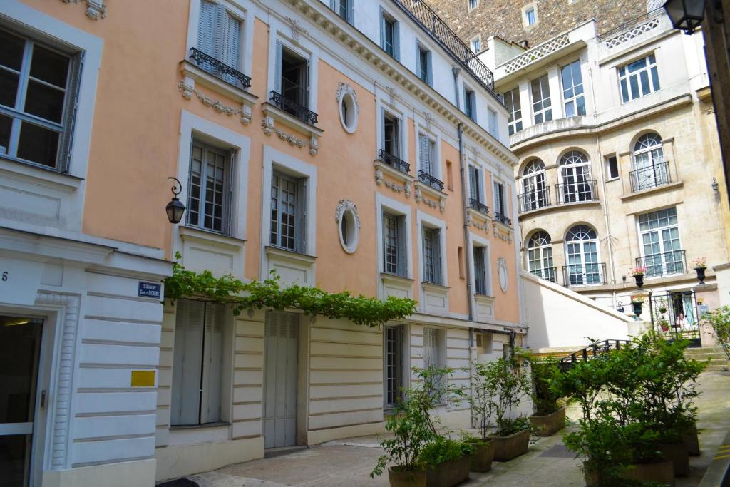 une rangée de bâtiments dans une rue avec des plantes dans l'établissement Le M. Musée du vin - l'appartement, à Paris