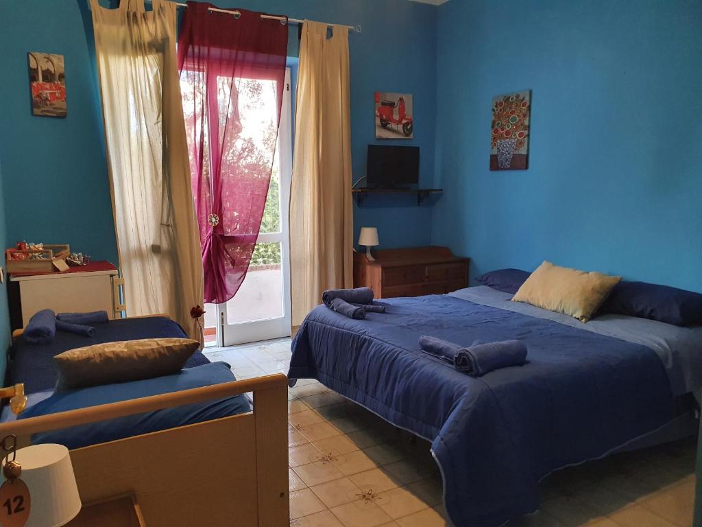 a blue bedroom with two beds and a window at La capannina cilento cam 12 in San Marco di Castellabate