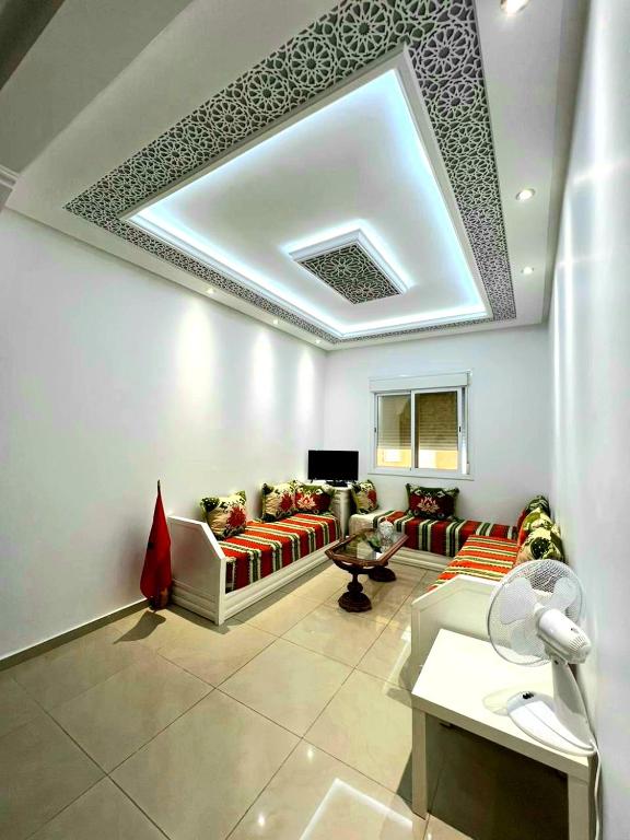 een woonkamer met banken en een plafond bij Appartement dans résidence à 2 pas de la mer et parking in Tanger