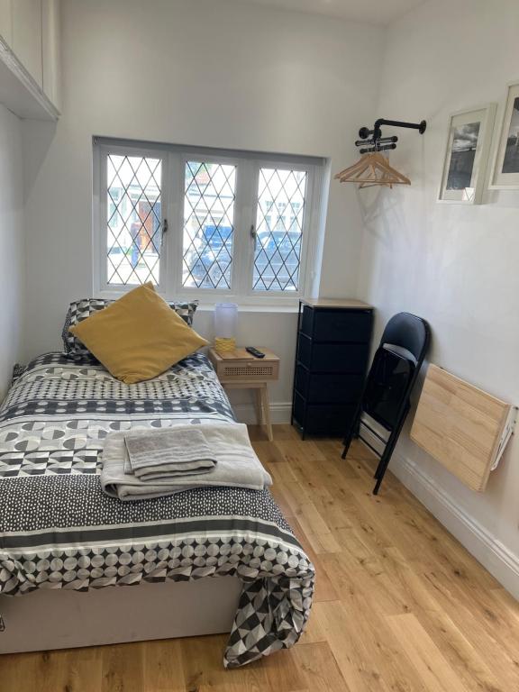 een slaapkamer met een bed, een bureau en 2 ramen bij Cosy Self Contained Apartment with private bathroom 10 mins to Wembley Stadium in Londen