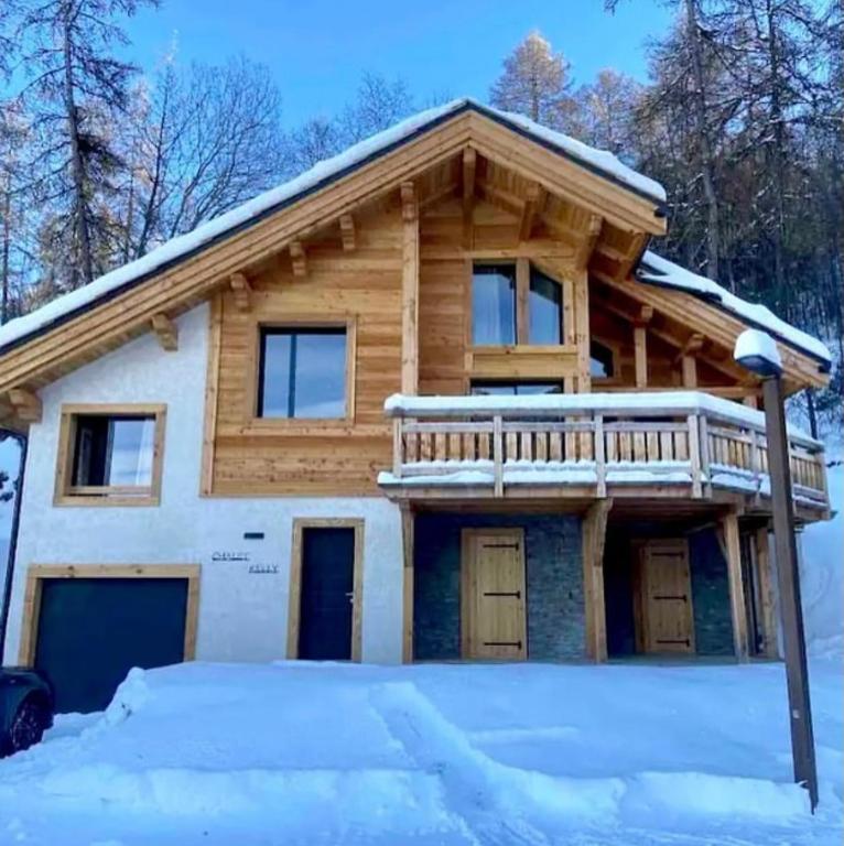 une maison en rondins avec une terrasse au sommet de la neige dans l'établissement Chalet Kelly, aux Orres