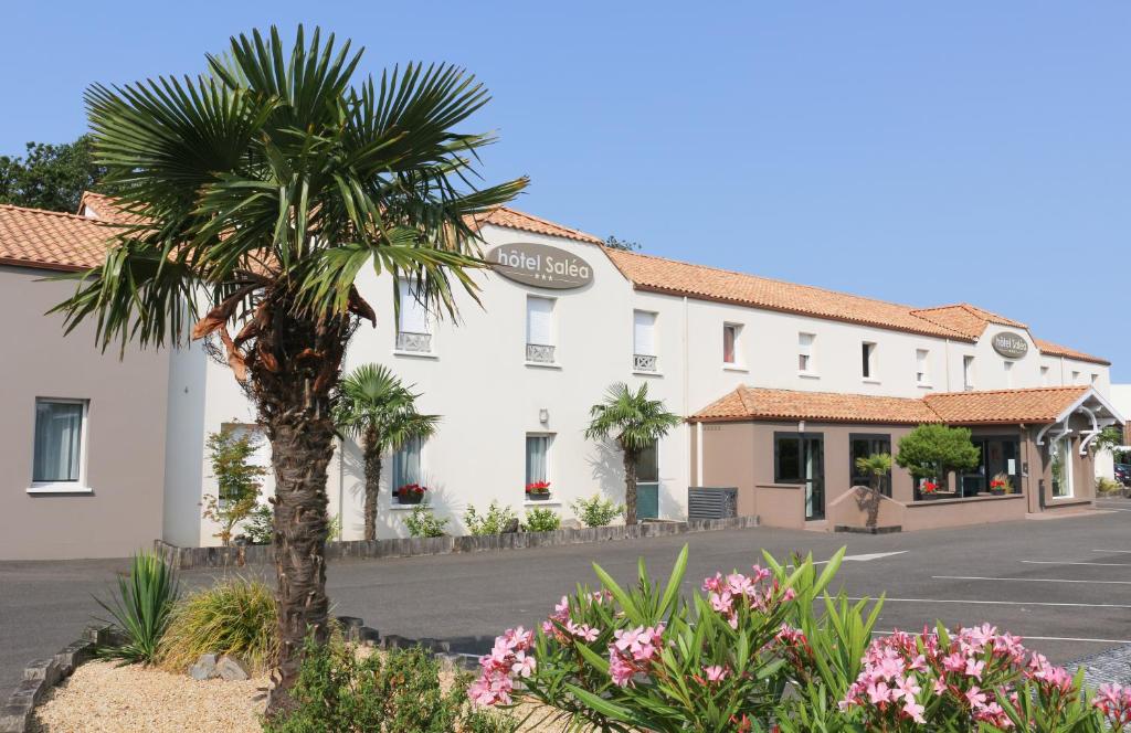 a building with a palm tree in front of a street at Hotel Salea in Pornic