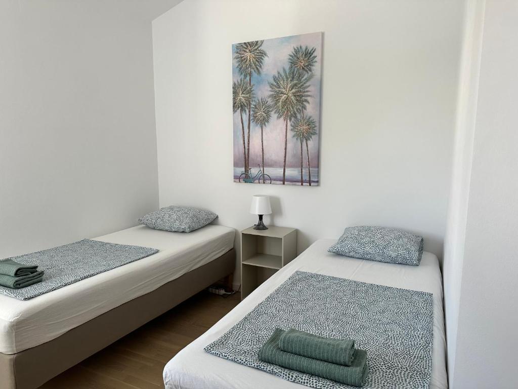 two beds in a room with palm trees on the wall at MINT Novalja Apartments in Novalja