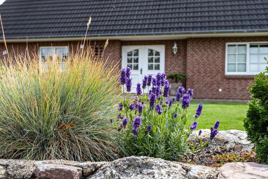 a house with purple flowers in front of a stone wall at Ferienwohnung Meeressand in Sankt Peter-Ording