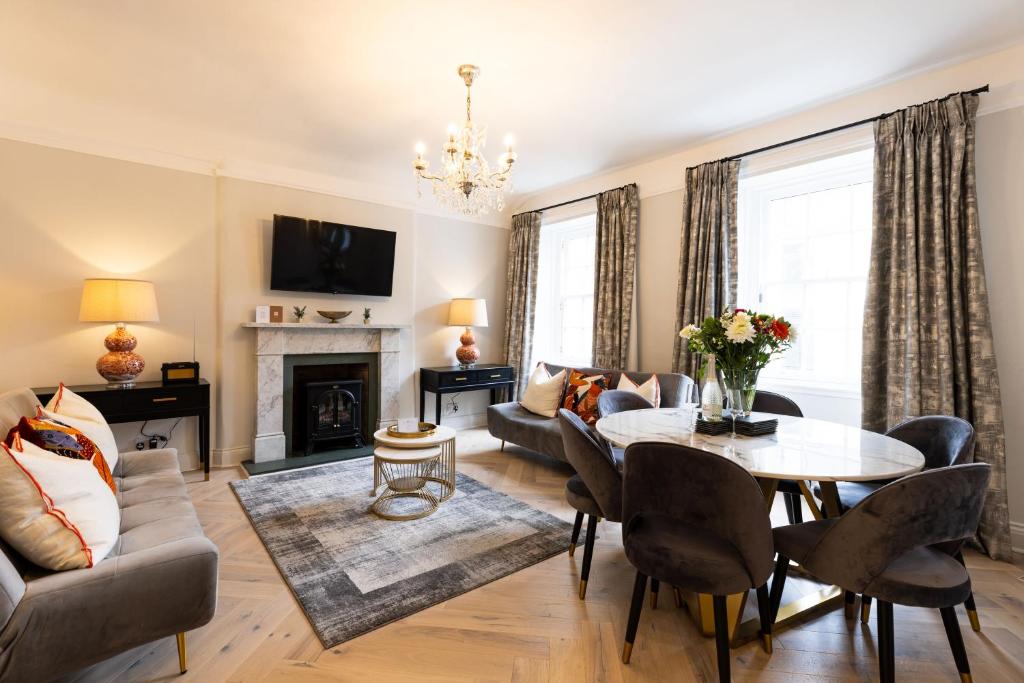 a living room with a table and chairs and a fireplace at RÌGH Properties - Luxurious City Centre Three Bedroom Apartment in Edinburgh