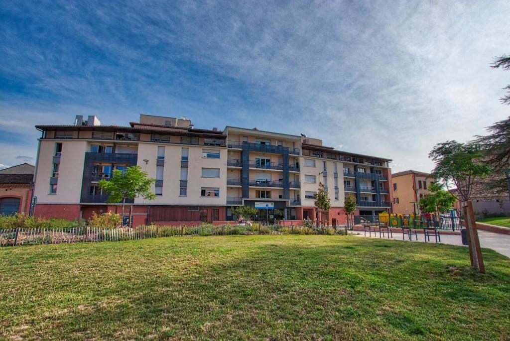 um grande edifício de apartamentos com um parque em frente em Zenao Albi - Résidence Stella em Albi