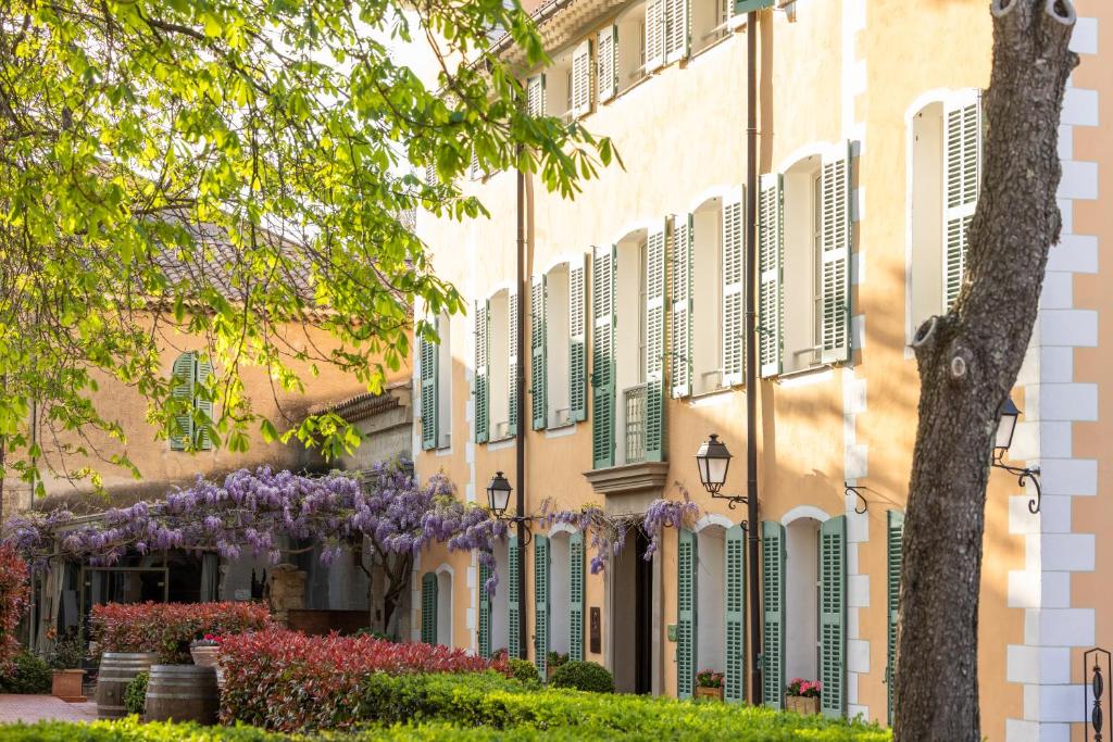 ein Gebäude mit grünen Fensterläden und lila Blumen in der Unterkunft Hostellerie De L'abbaye De La Celle - Teritoria in La Celle