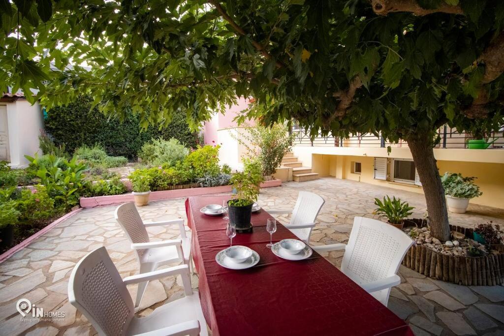 una mesa roja y sillas blancas en un jardín en Odysseus Cozy Home, en Nea Makri