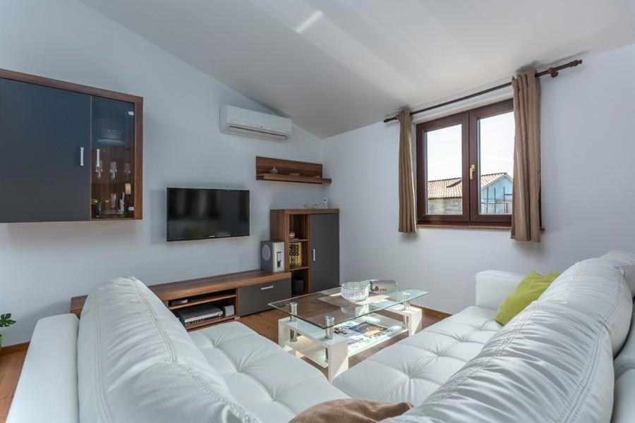 a living room with a white couch and a tv at Valeria Apartment in Vabriga