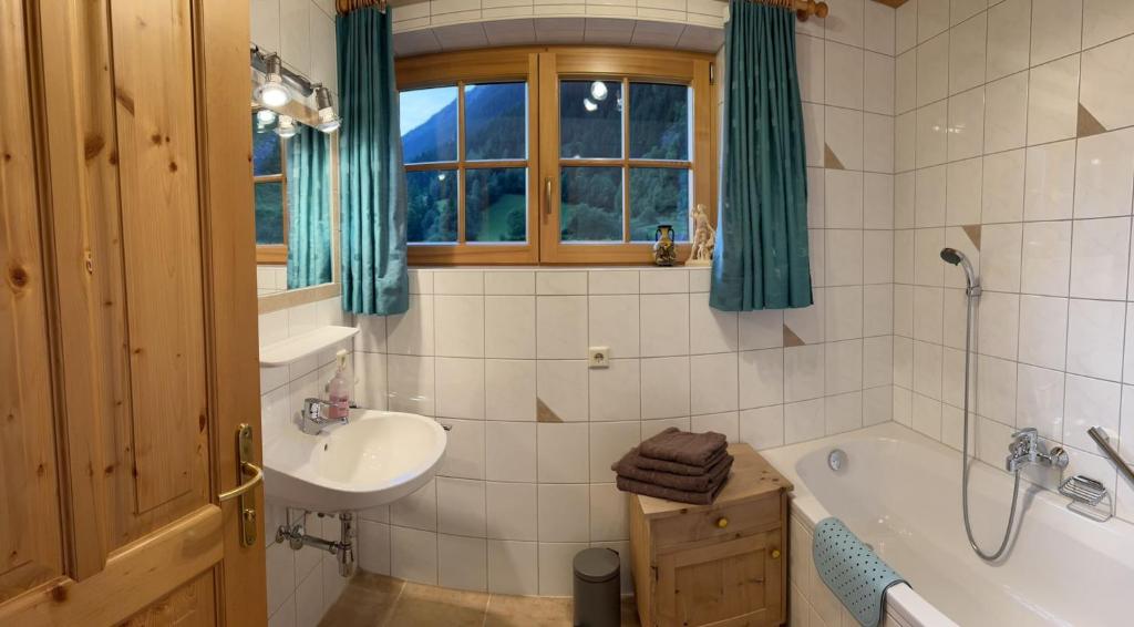 y baño con bañera, lavamanos y bañera. en Apart Onkl, en Sankt Leonhard im Pitztal