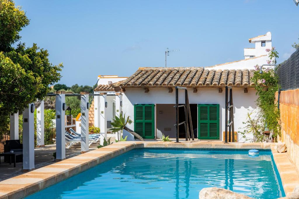 uma piscina em frente a uma casa com persianas verdes em Sa Casa des Pintor Miquel Vives 213 em Cala Bona