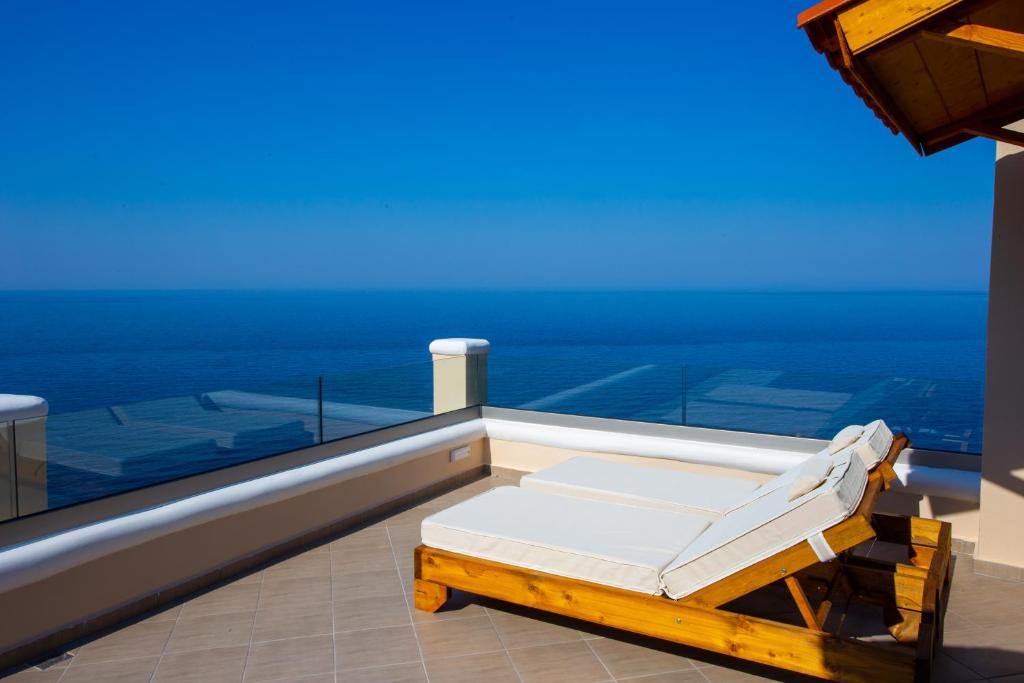 a bed on a balcony with the ocean in the background at The Life Suites in Limnionas