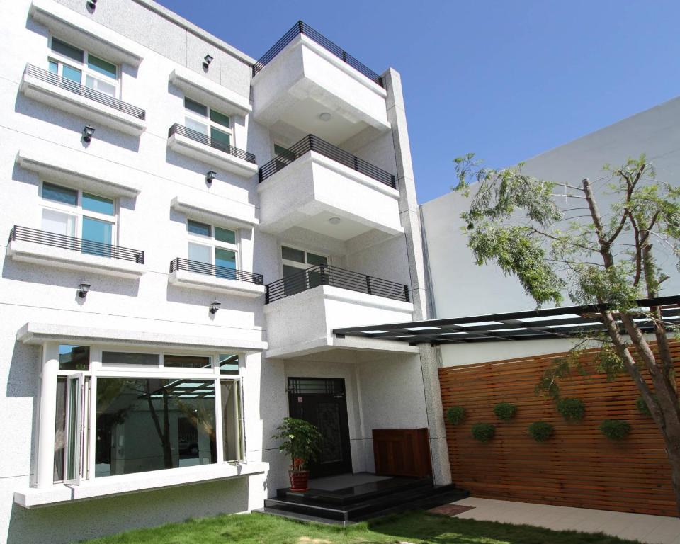 a white building with balconies and a yard at Normans B&B in Hualien City