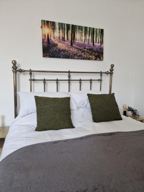 una camera da letto con un letto con lenzuola bianche e cuscini verdi di Direct Booking Prices, Studio Apartment, Free Parking, Wifi, Central, Quiet a Exeter