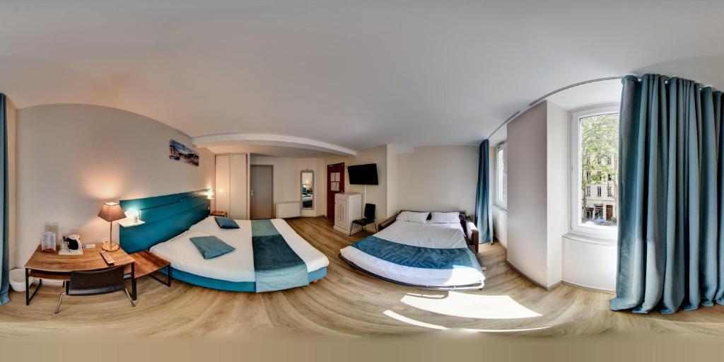 a bedroom with two beds and a living room at Hôtel du Parc in Lyon