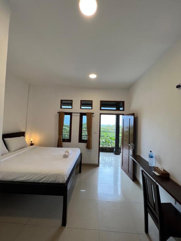 a bedroom with a bed and a desk and windows at Ocean Breeze Uluwatu Apartments in Uluwatu