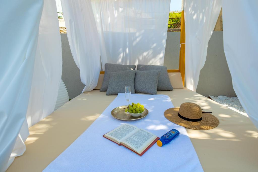 łóżko z kapeluszem, książką i talerzem winogron w obiekcie Villa Mirjam with swimming pool, jacuzzi and sea view w Novim Vinodolskim