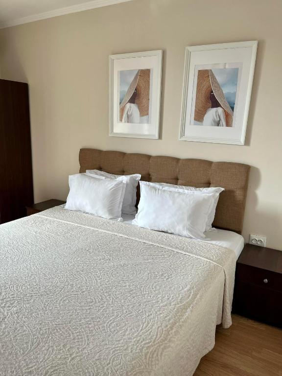 a bedroom with a white bed with two pictures on the wall at Red House Family Hotel in Ravda