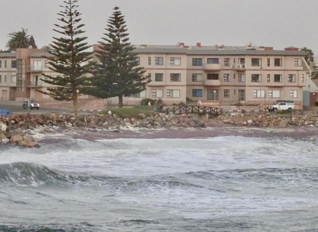 a beach with a building and trees and the ocean at 1 bedroom Morleen Park apartment in Swakopmund