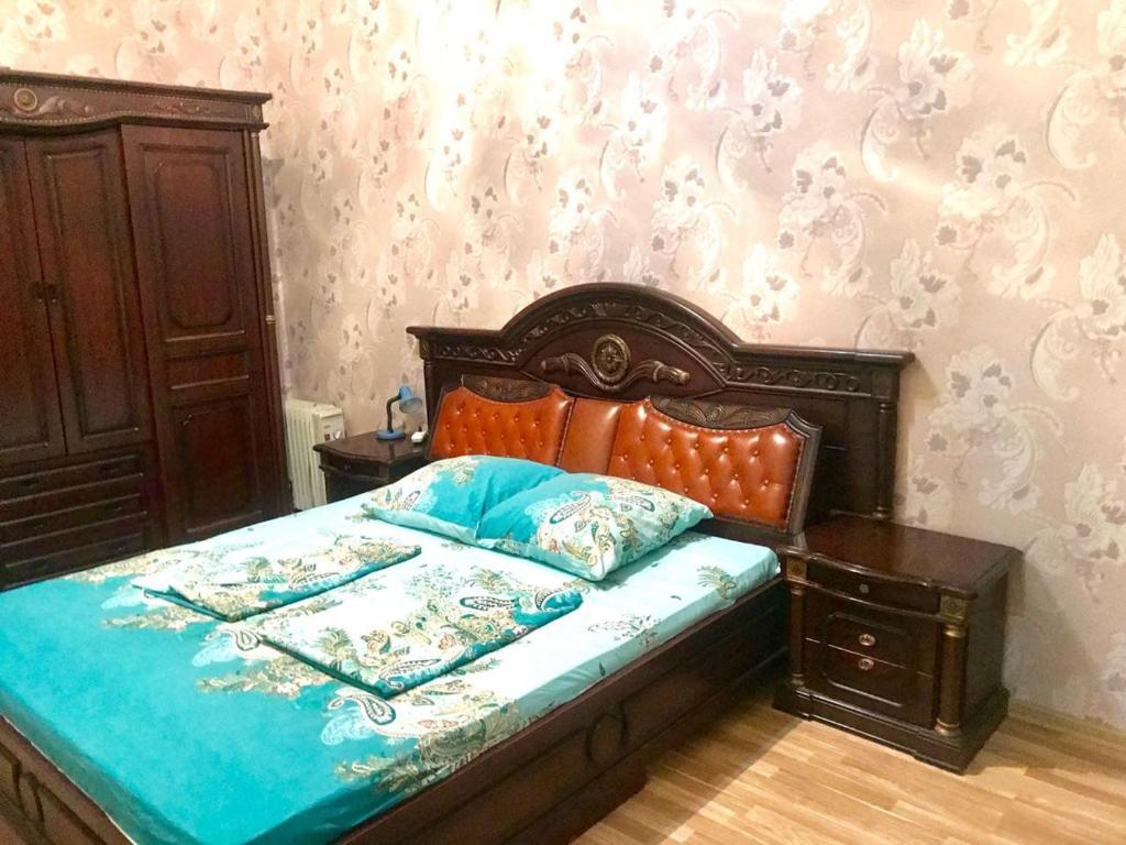 a bedroom with a bed with a wooden head board at Cozy, large apartment in the heart of city center in Baku
