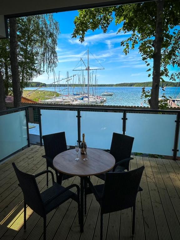a table and chairs on a deck with a boat in the water at Lago Apartamenty Domki in Niesulice