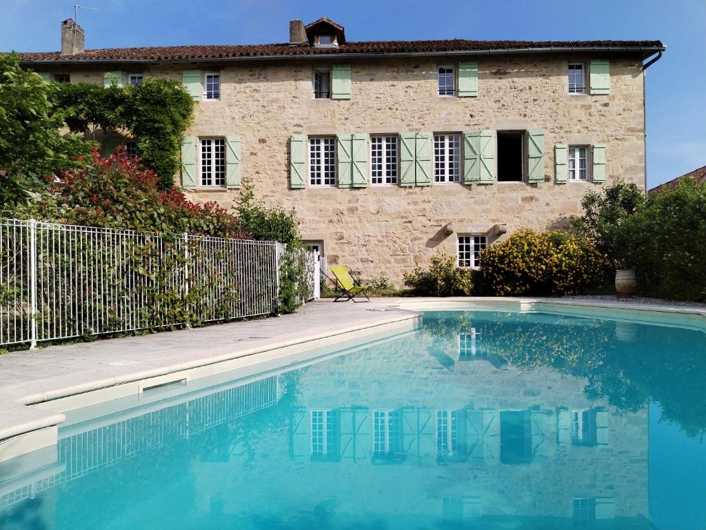 a house with a swimming pool in front of a building at ensemble de deux chambres pour famille in Planioles