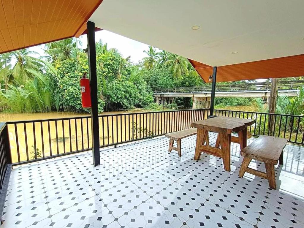 a patio with a table and a bench on a balcony at Amantra homestay & village in Surat Thani