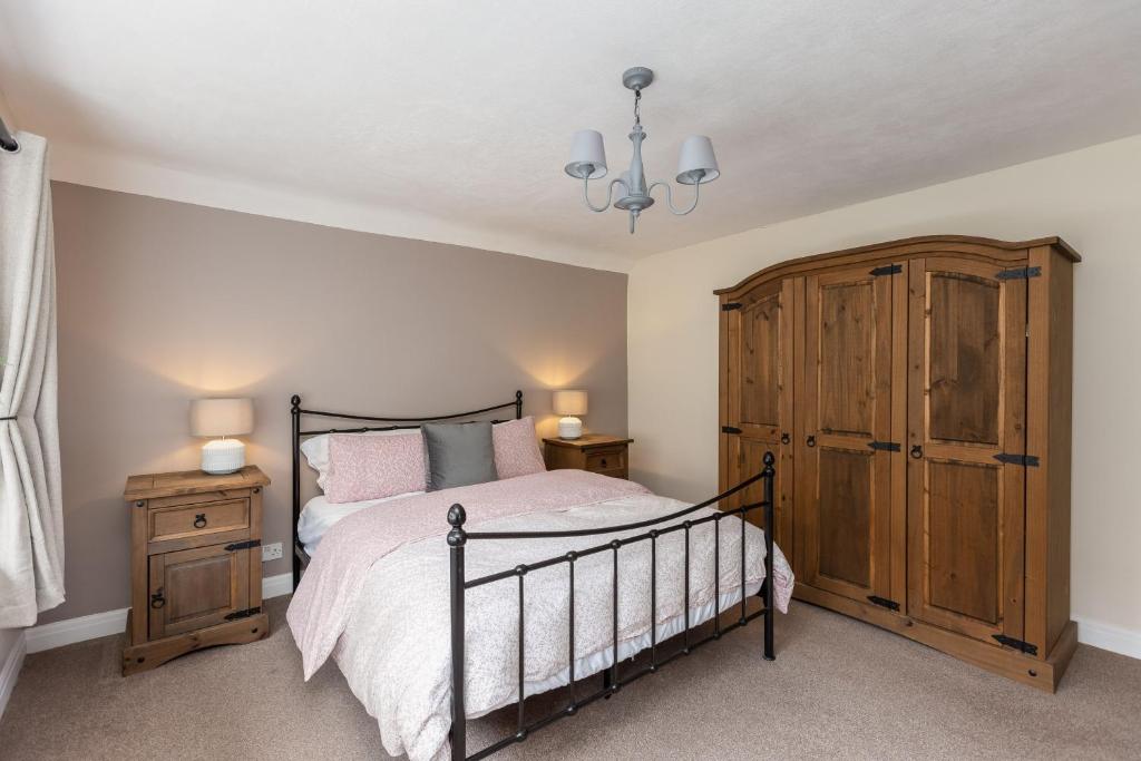 a bedroom with a bed and a wooden cabinet at Broomfield Cottage Nr Pickering - DOGS STAY FOR FREE in Pickering