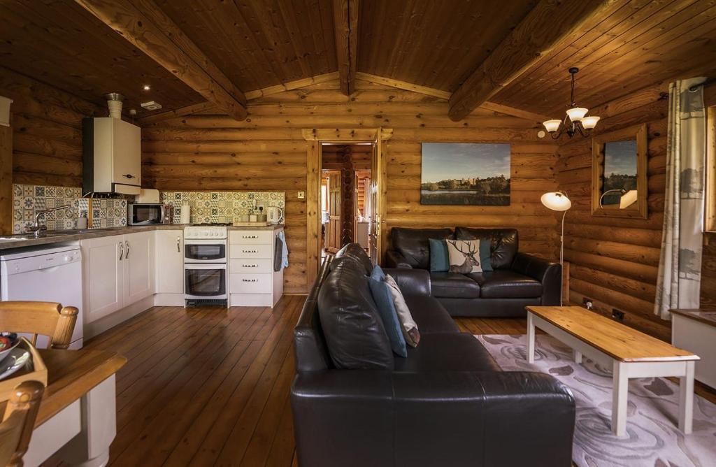 a living room with a black leather couch in a cabin at Bullfinch - 2 Bed Lodge in Saxtead
