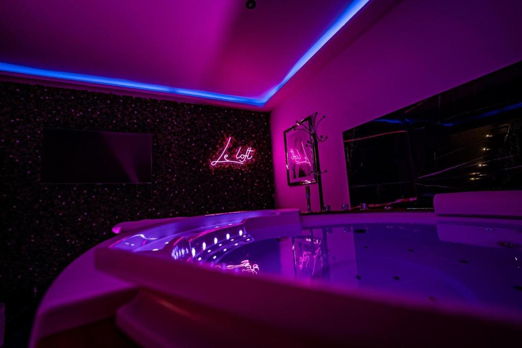 ein Badezimmer mit violetter Beleuchtung und einer Badewanne mit einem TV in der Unterkunft Le Loft Nancy in Nancy