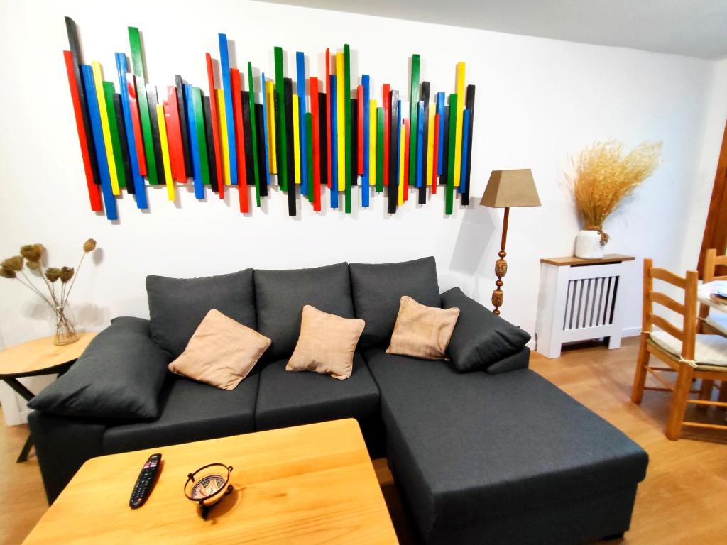 uma sala de estar com um sofá preto e arte colorida na parede em Reformado a estrenar a 1 minuto estación Tren-Bus Vialia Vigo em Vigo