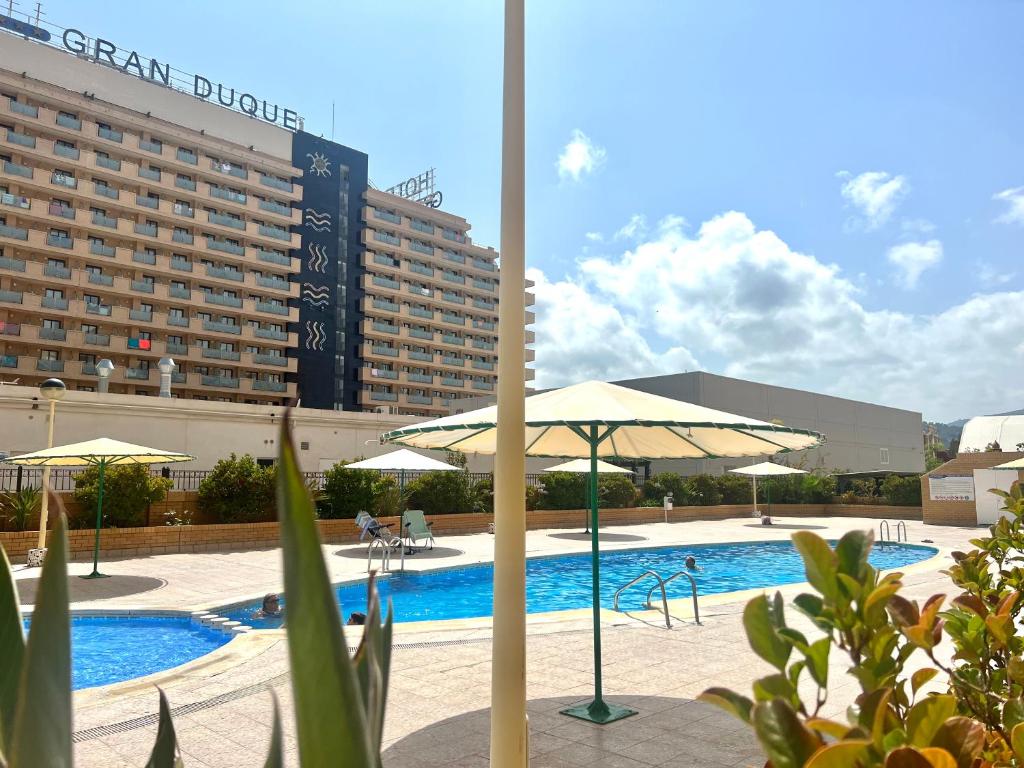 una piscina con sombrilla y un hotel en Apartamentos Deluxe Marina Dor, en Oropesa del Mar