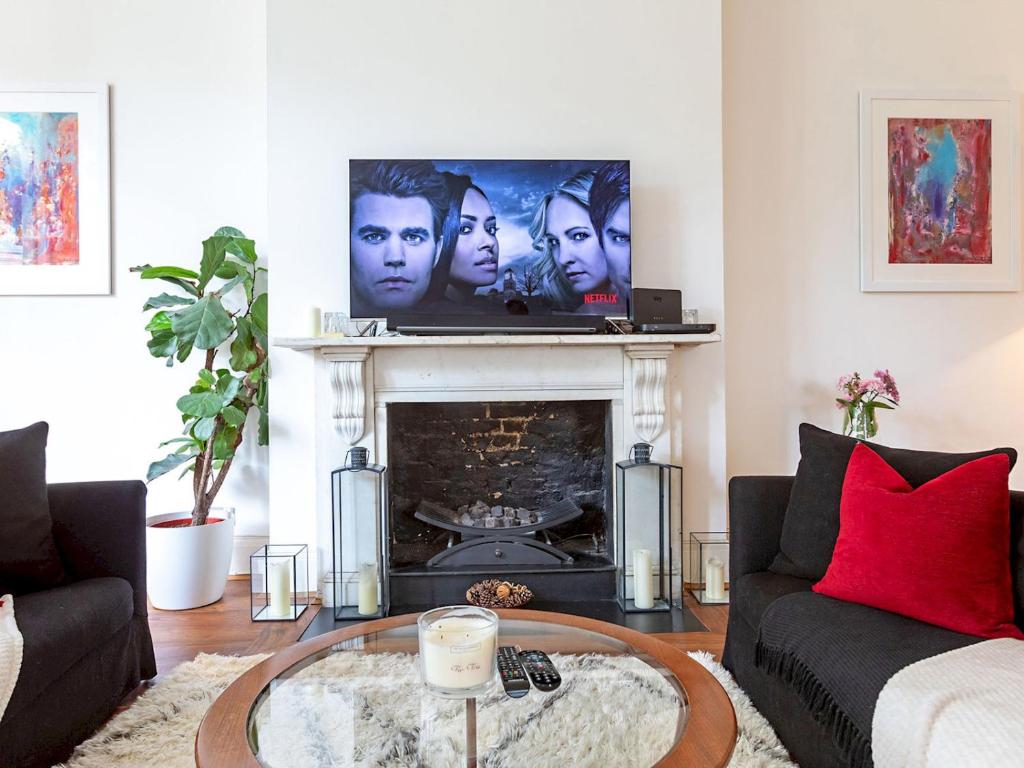 a living room with a tv above a fireplace at Pass The Keys Perfect Blend of Comfort Charm in London