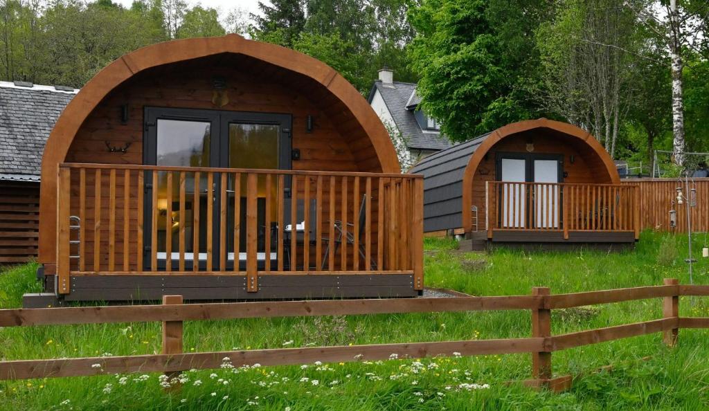 uma cabina de madeira com um deque e uma vedação em Pinemarten Lodge em Roybridge
