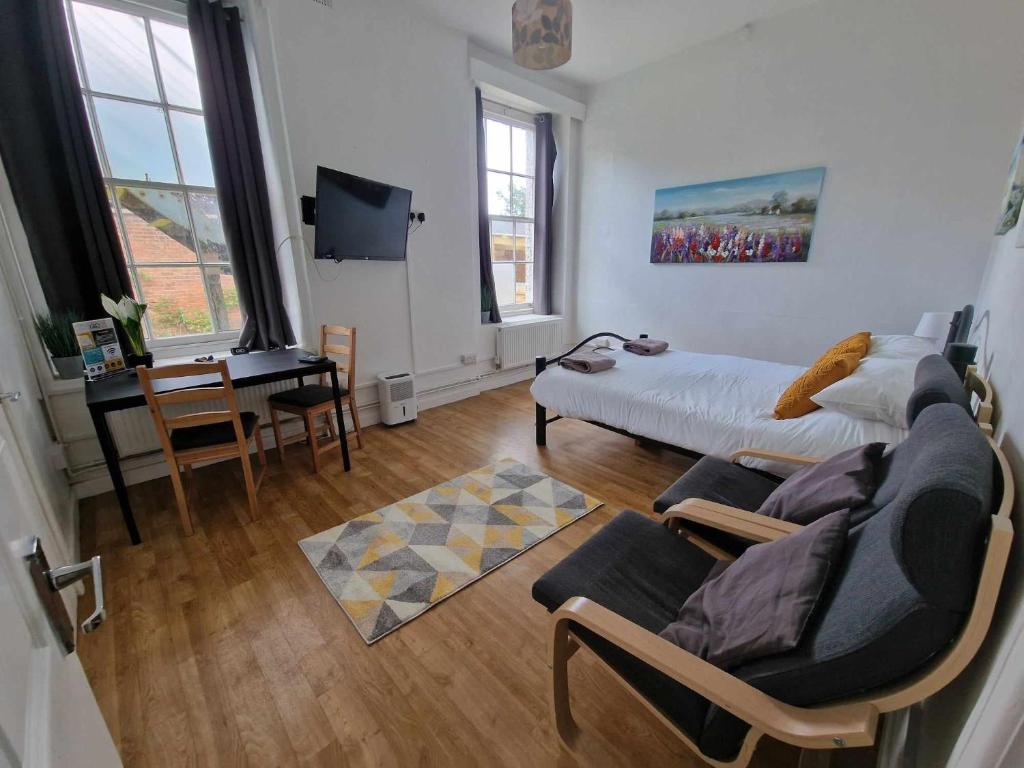 a bedroom with a bed and a chair and a desk at Studio Apartment, Private Parking, Walk To Centre, Uni and Hospital, Long Stay Prices in Exeter