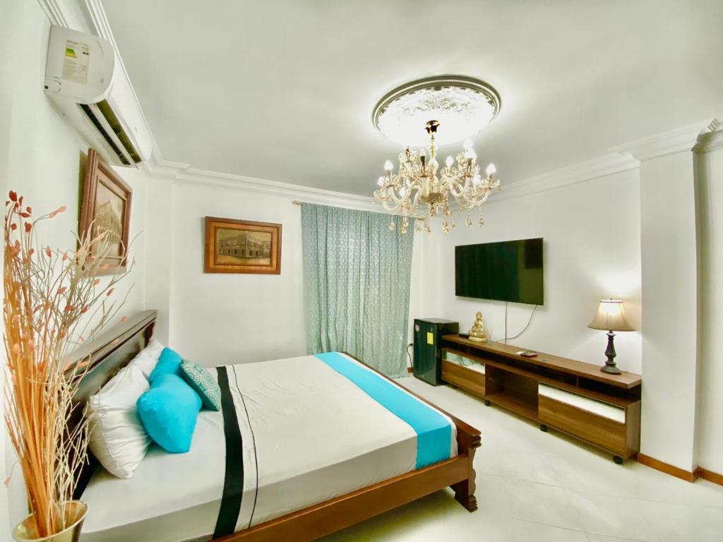 um quarto com uma cama, uma televisão e um lustre em Big House em Guayaquil