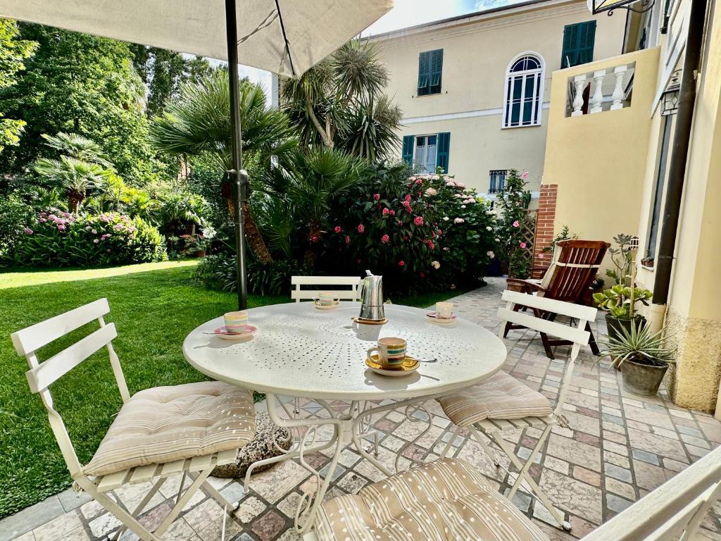 een witte tafel en stoelen op een patio met een parasol bij Villa Angelina Casa Limone in Vallecrosia