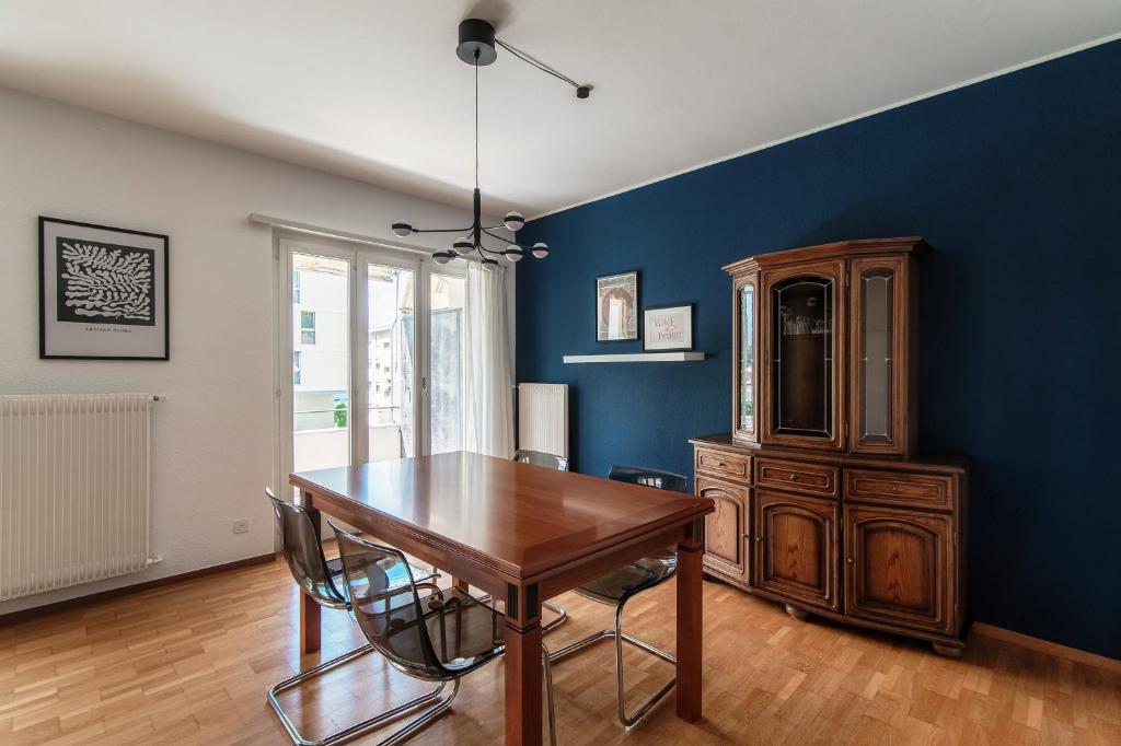 ein Esszimmer mit einem Holztisch und einer blauen Wand in der Unterkunft Victoria Apartment by Quokka 360 - simple and practical flat in Locarno in Solduno