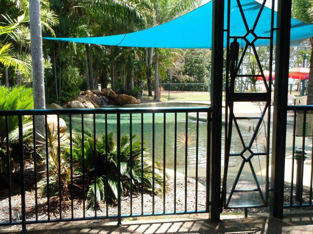 uma vista para uma piscina a partir de um portão num jardim zoológico em Bushland Beach Tavern em Townsville