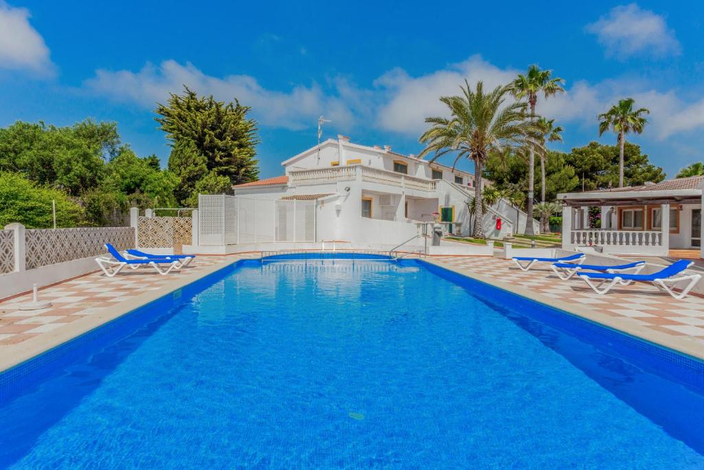 a swimming pool with chairs and a house at Apartamento con estupenda terraza-a4 in Son Xoriguer