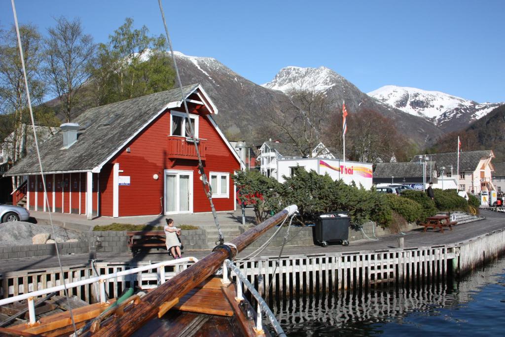 ein rotes Haus neben einem Dock mit Bergen in der Unterkunft Skålafjæro 25 in Rosendal