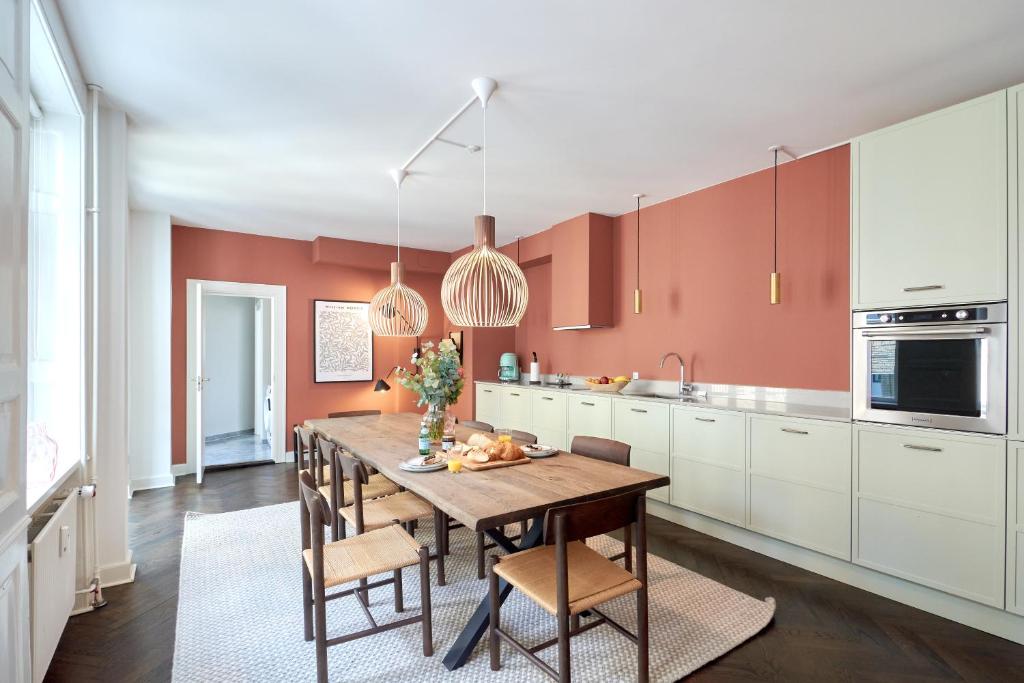 uma cozinha com uma mesa de madeira e cadeiras em Large 4 bedroom with Balcony & Bathtub in CPH City em Copenhague