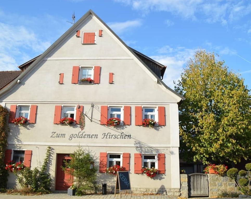 a white house with red shuttered windows and flowers at Schwemmers "Alter Stall" in Bad Windsheim