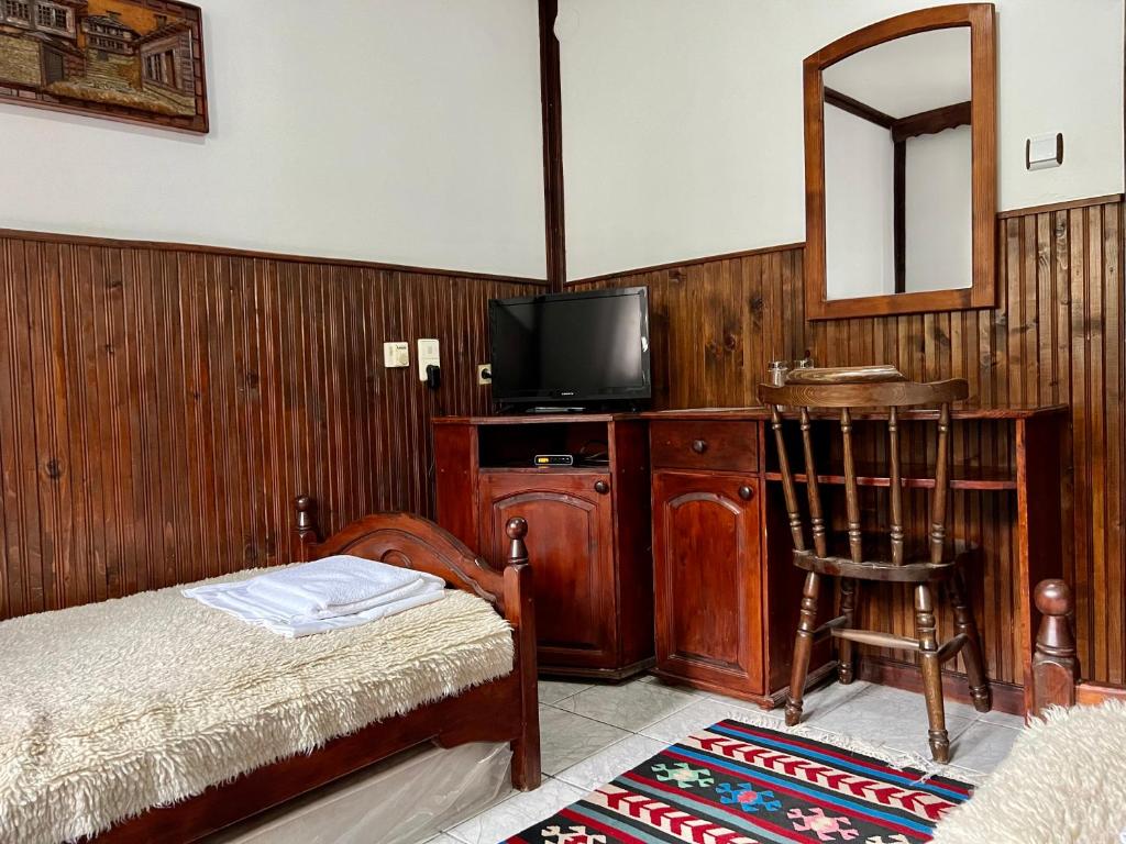 a bedroom with a bed and a tv and a chair at Хотел механа Караджейката 