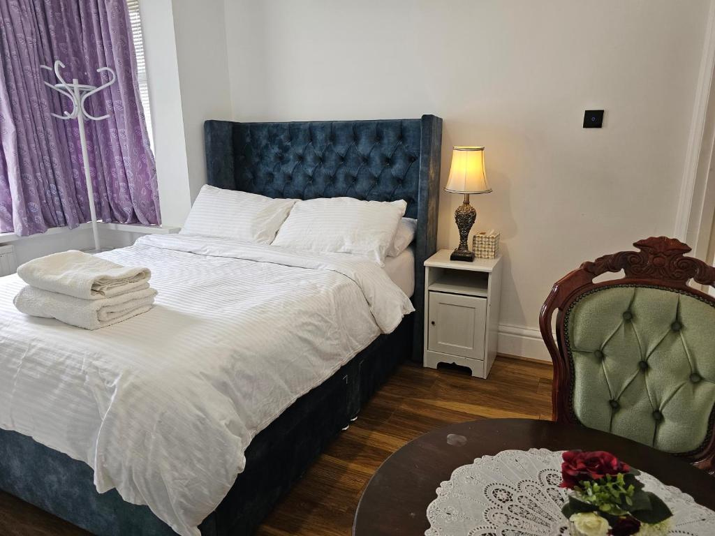a bedroom with a bed with a blue headboard and a table at Lovely Rooms London in London