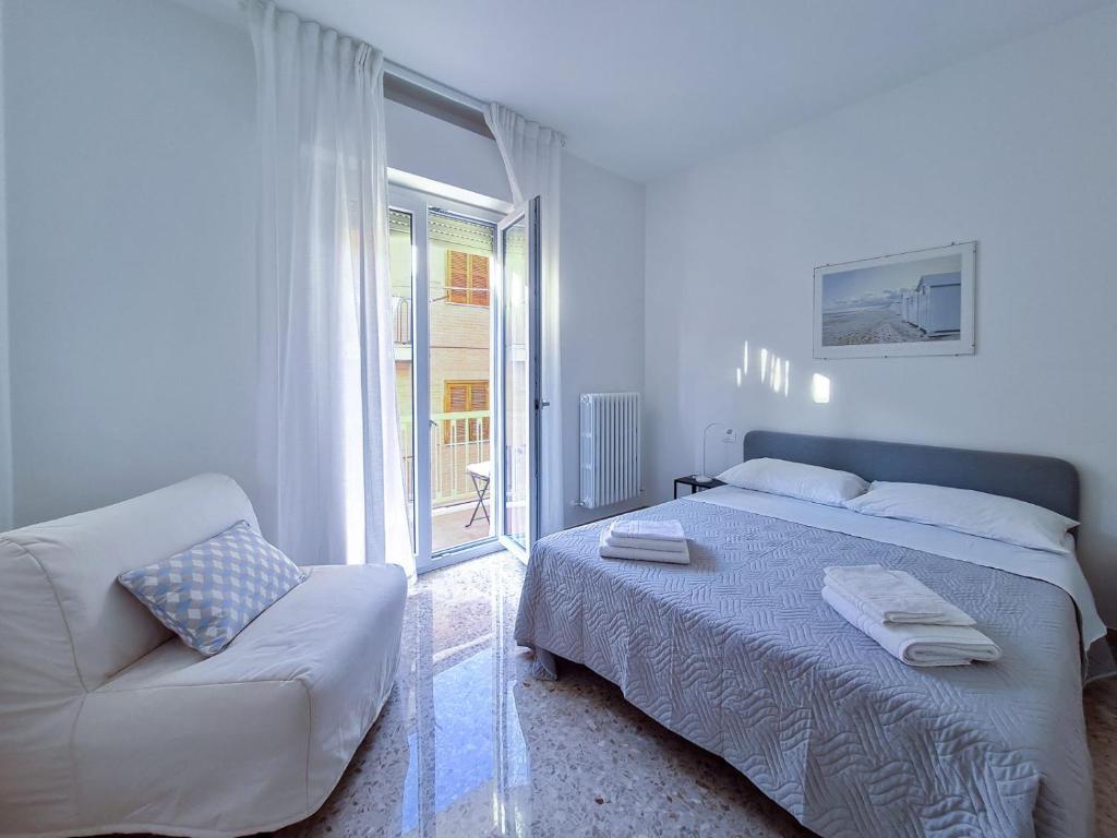 een slaapkamer met een bed, een bank en een raam bij La Roscia House in Porto San Giorgio