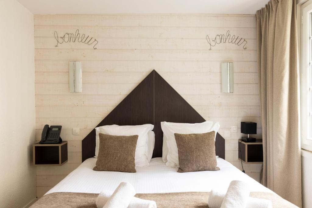 a bedroom with a bed with white sheets and pillows at Hotel Le Dauphin in Honfleur